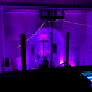 Die in blau und violett angestrahlte Christuskirche von der Empore fotografiert. Im Vordergrund ein beleuchtetes Mischpult und ein Stativ mit Scheinwerfern, dahinter die hohe Balustrade.