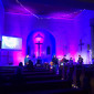 Die in blau und violett angestrahlte Christuskirche von hinten fotografiert, vorne spielt die Band.