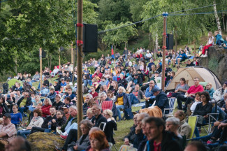 Besucher:innen sitzen im Grünen bei der Pfingsttagung