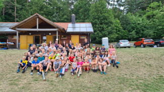 Gruppenbild: Teilnehmende und Betreuende im Grünen vor einer Hütte